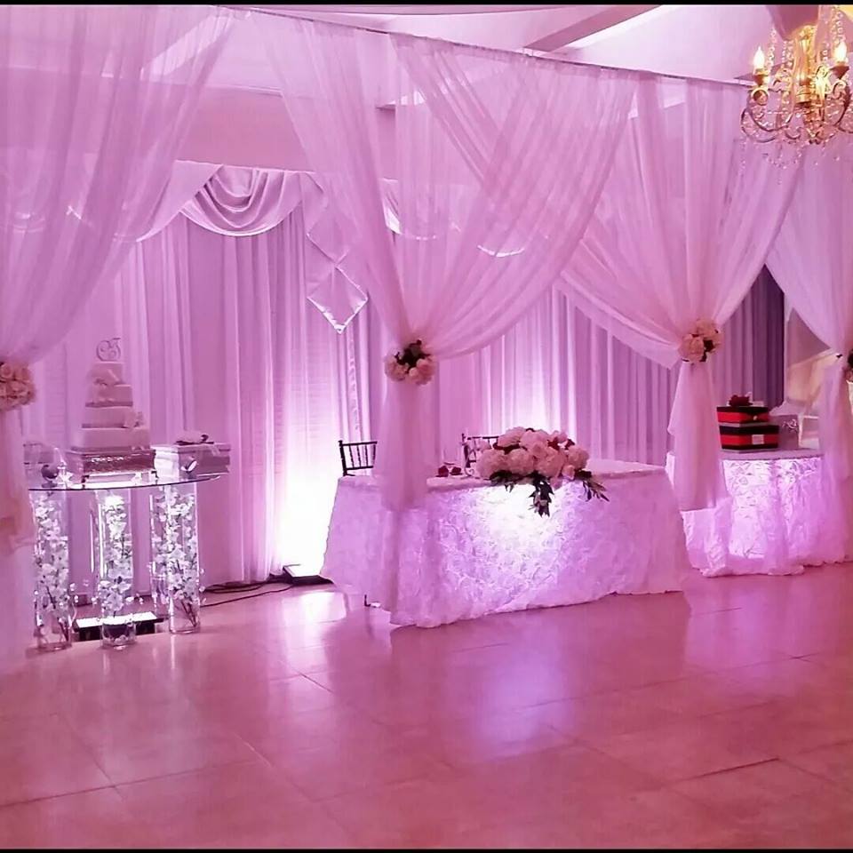Elegant pink-themed event setup with draped fabric and floral decorations.