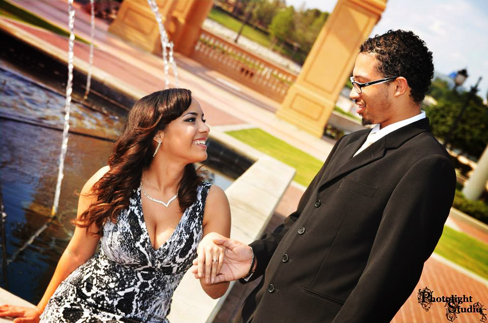 A couple holding hands and smiling at each other outdoors.