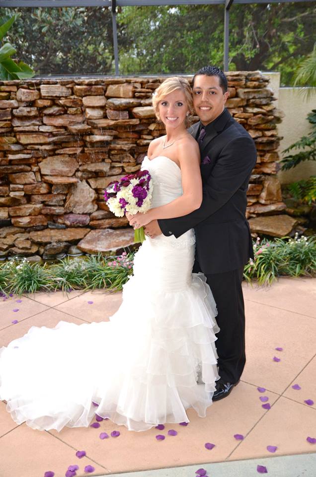 Bride and groom posing outdoors in wedding attire.