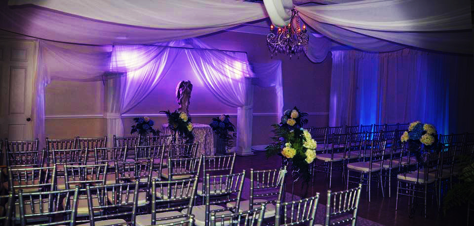 Elegantly decorated event space with purple lighting and floral arrangements.