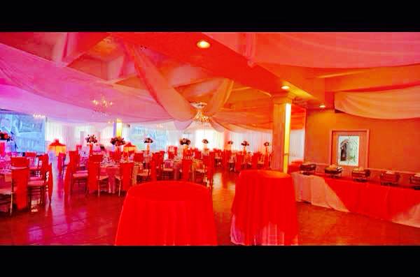 Event space decorated with red and orange lighting and draped fabric.