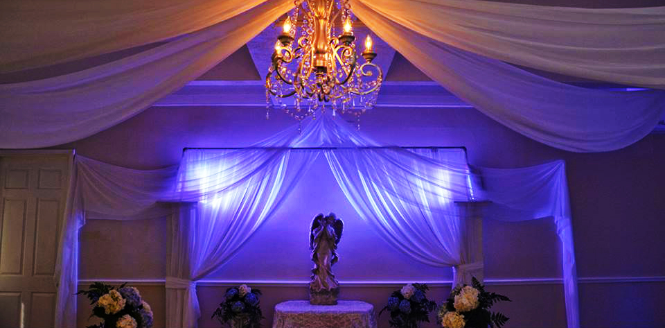 Romantic wedding altar with draped fabric and chandelier lighting.