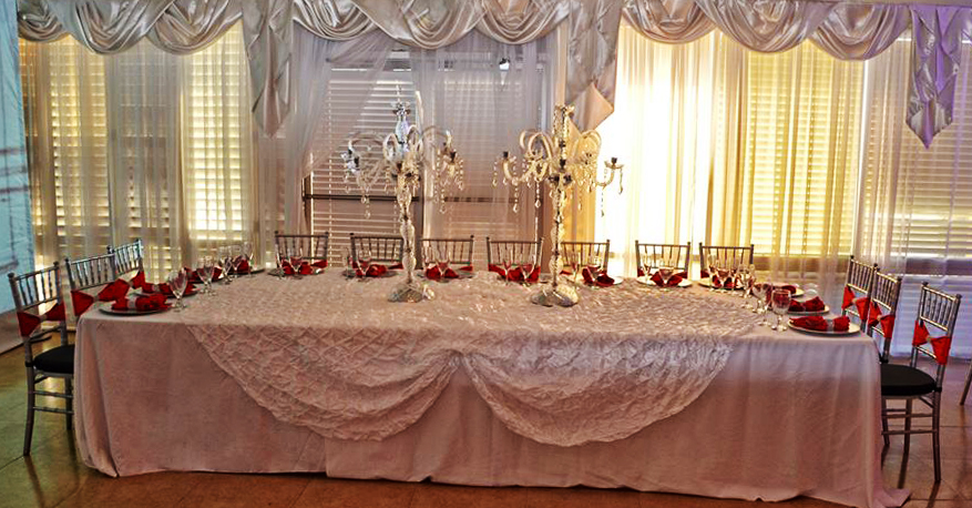 Elegant wedding head table with lace tablecloth and candelabras.