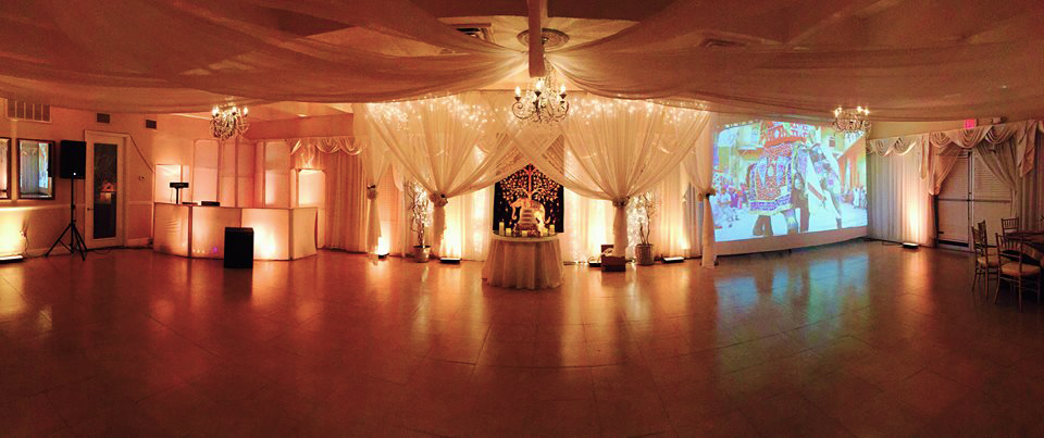 Elegant wedding reception setup with draped white fabric and warm lighting.