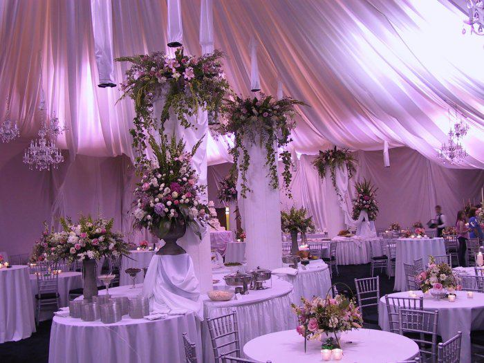 Elegant wedding reception setup with floral decorations and soft purple lighting.