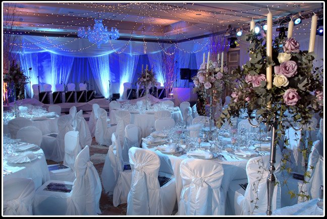 Elegant wedding reception setup with white chairs and floral centerpieces.