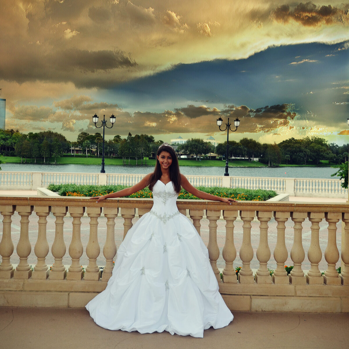 Bride in a white wedding gown poses by a balcony under a dramatic sky.