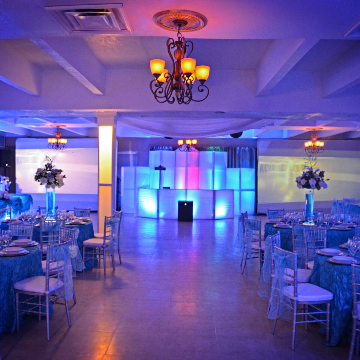 Elegant event hall with blue lighting and chandeliers.