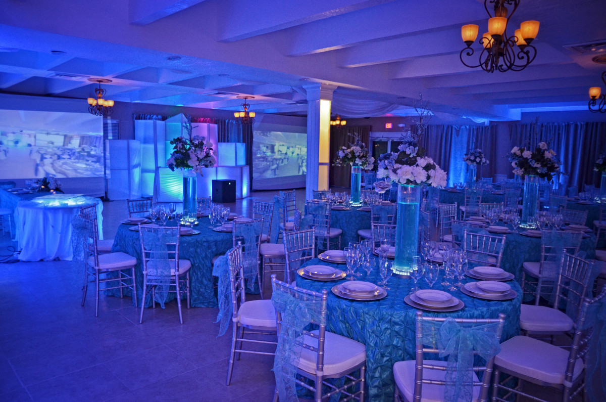 Elegant banquet hall with blue lighting and round tables set for an event.
