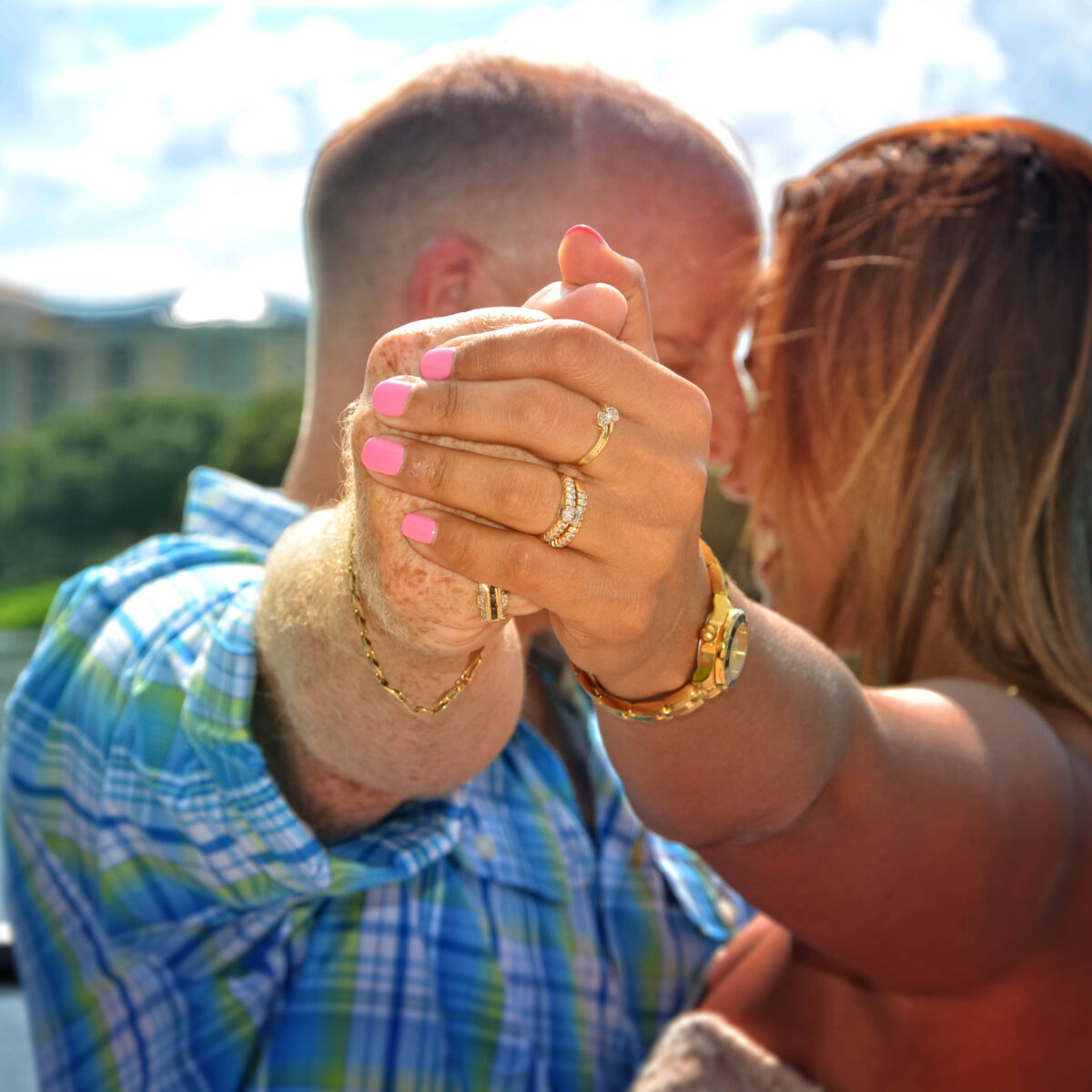 Couple holding hands closely, showing an engagement ring.