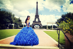Woman in a vibrant blue gown posing near the Eiffel Tower.